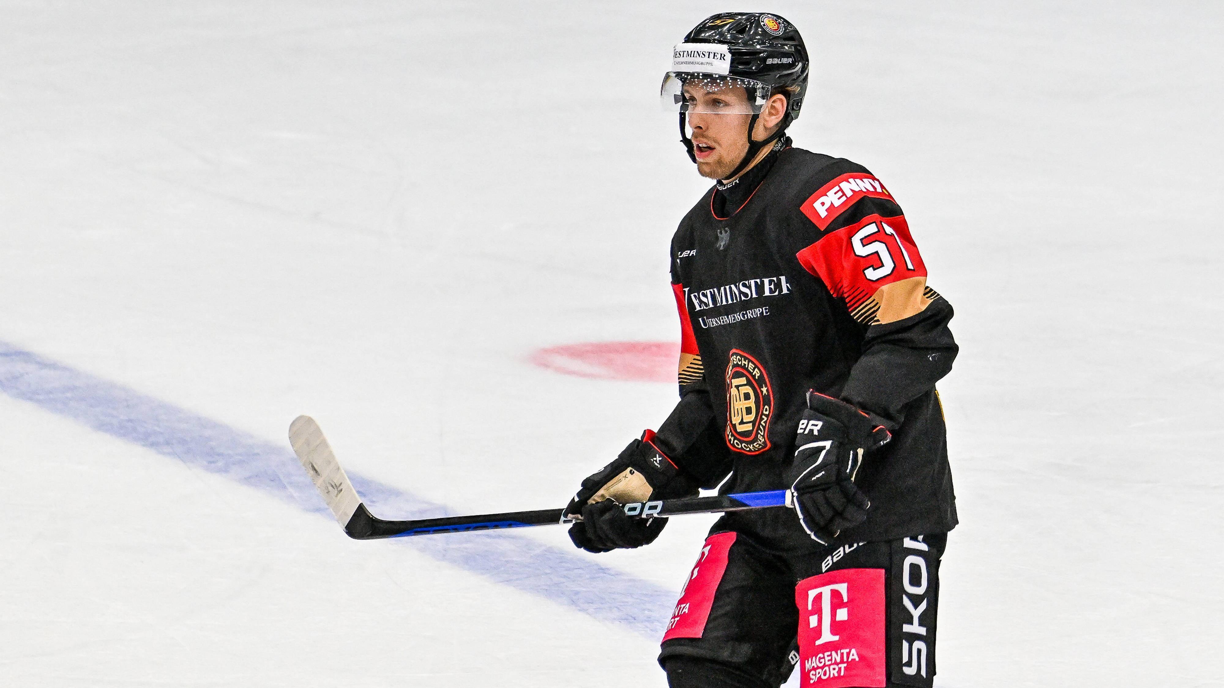 Leon Hüttl vom DEB-Team steht auf dem Eis und blickt in Richtung Spielgeschehen